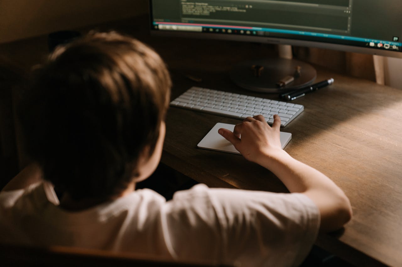 Teenager coding on a computer from a warm and cozy indoor setting, focused on software development.