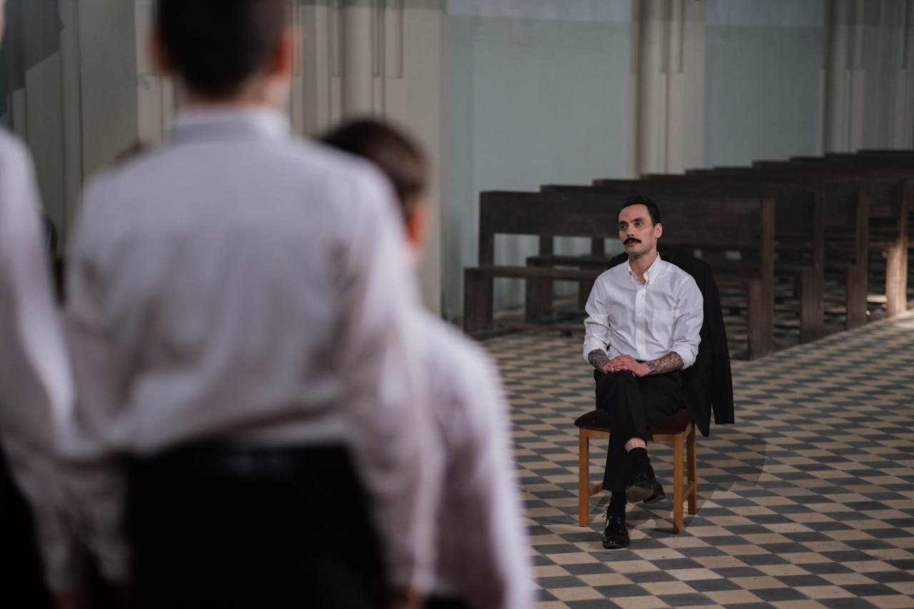 Conductor observes choir boys performing during practice in a church setting.